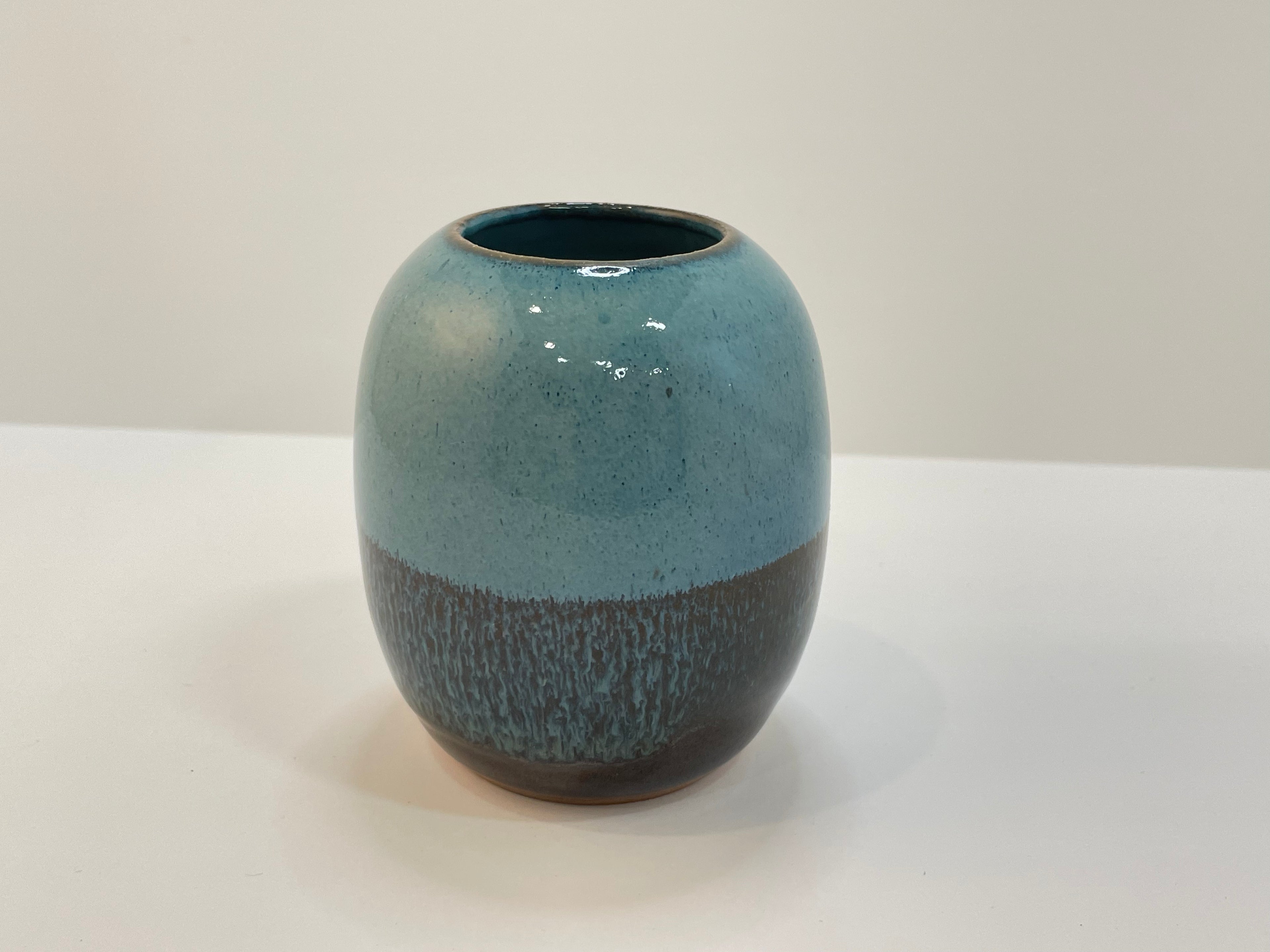 Ceramic vase with blue and brown glaze on a white background